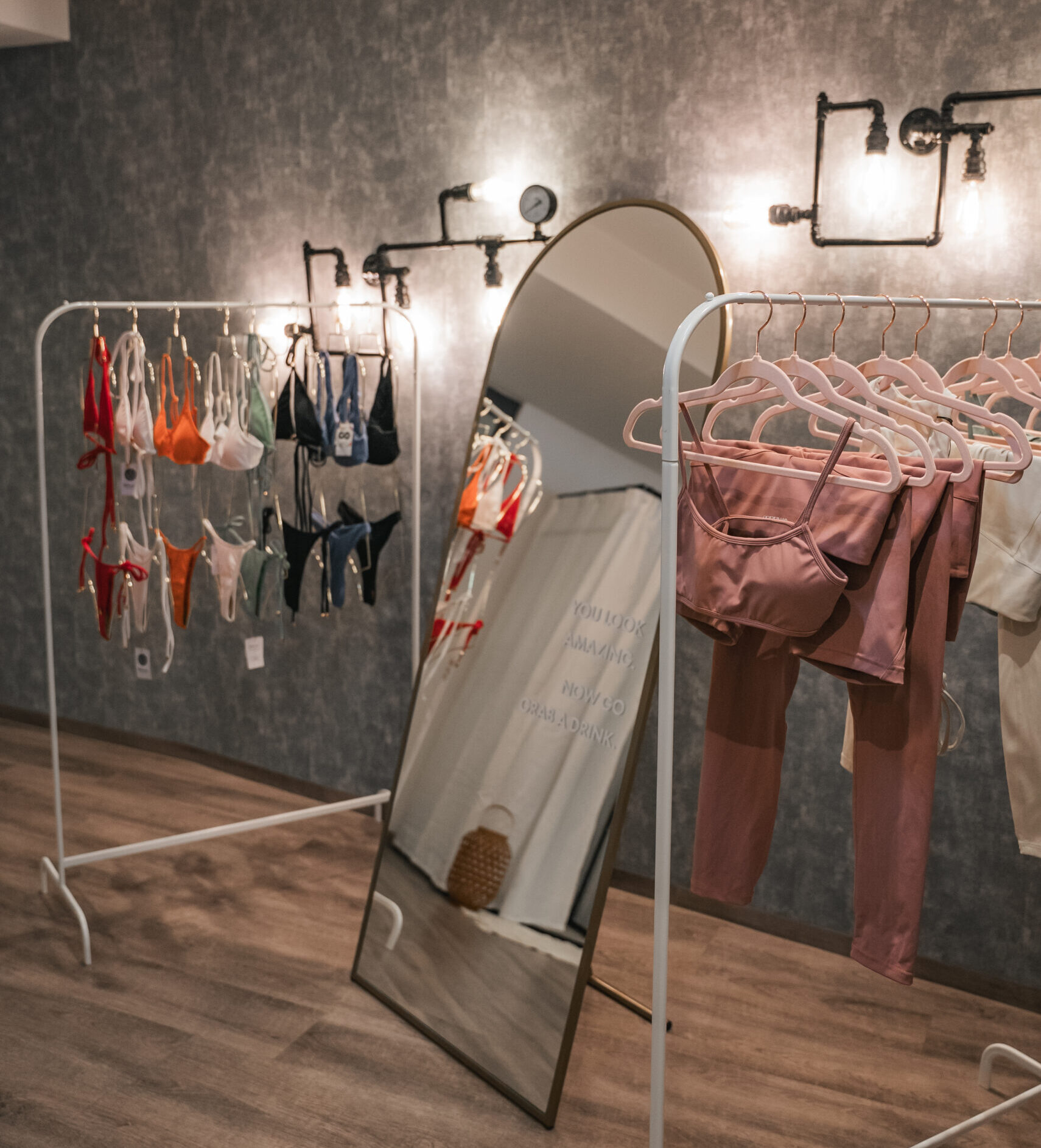Bikinis und Sportkleidung auf Kleiderständer mit Spiegel in der Mitte