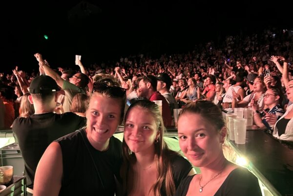 Drei Frauen hinter einer Bartheke bei einem Konzert abends mit Publikum im Hintergrund