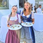 zwei Frauen in Dirndl mit Speisentellern in der Hand im Garten des Zocklwirt