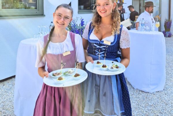 zwei Frauen in Dirndl mit Speisentellern in der Hand im Garten des Zocklwirt