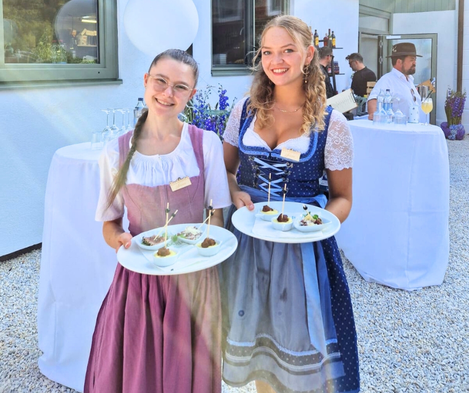 zwei Frauen in Dirndl mit Speisentellern in der Hand im Garten des Zocklwirt