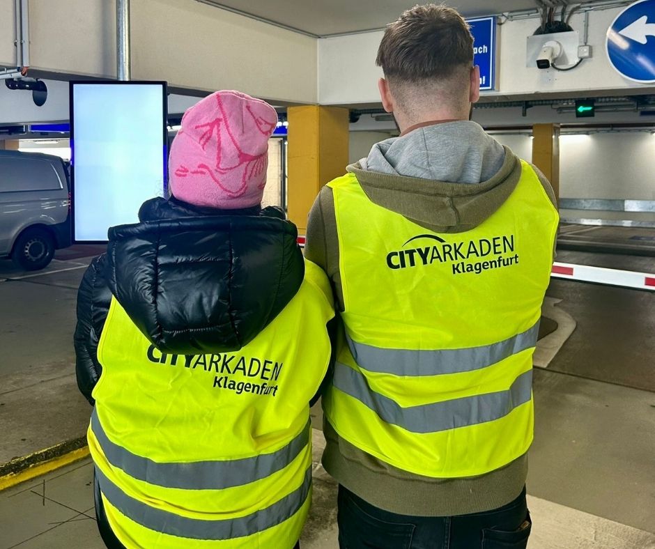 zwei Personen mit Warnwesten mit City Arkaden Aufschrift von hinten