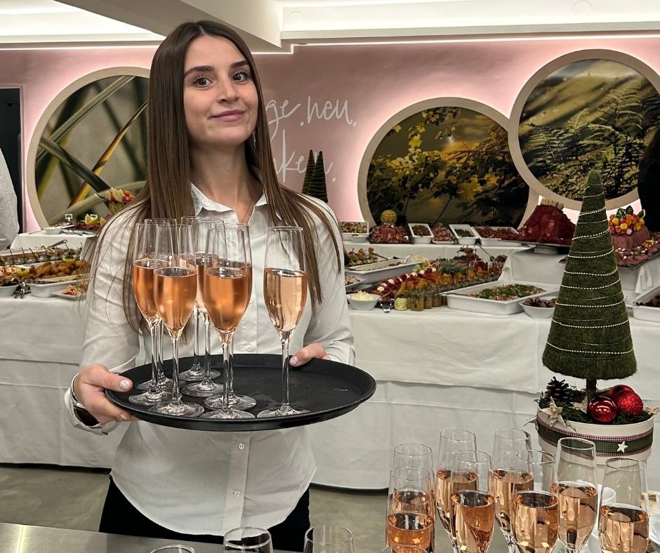 Frau trägt Tablett mit Sektgläsern